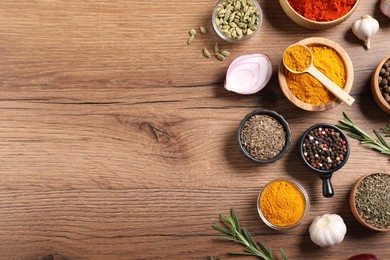 Photo of Different aromatic spices on wooden table, flat lay. Space for text
