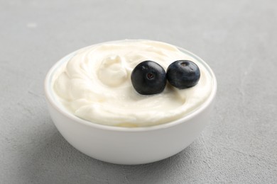Photo of Delicious yogurt with blueberries in bowl on grey table, closeup