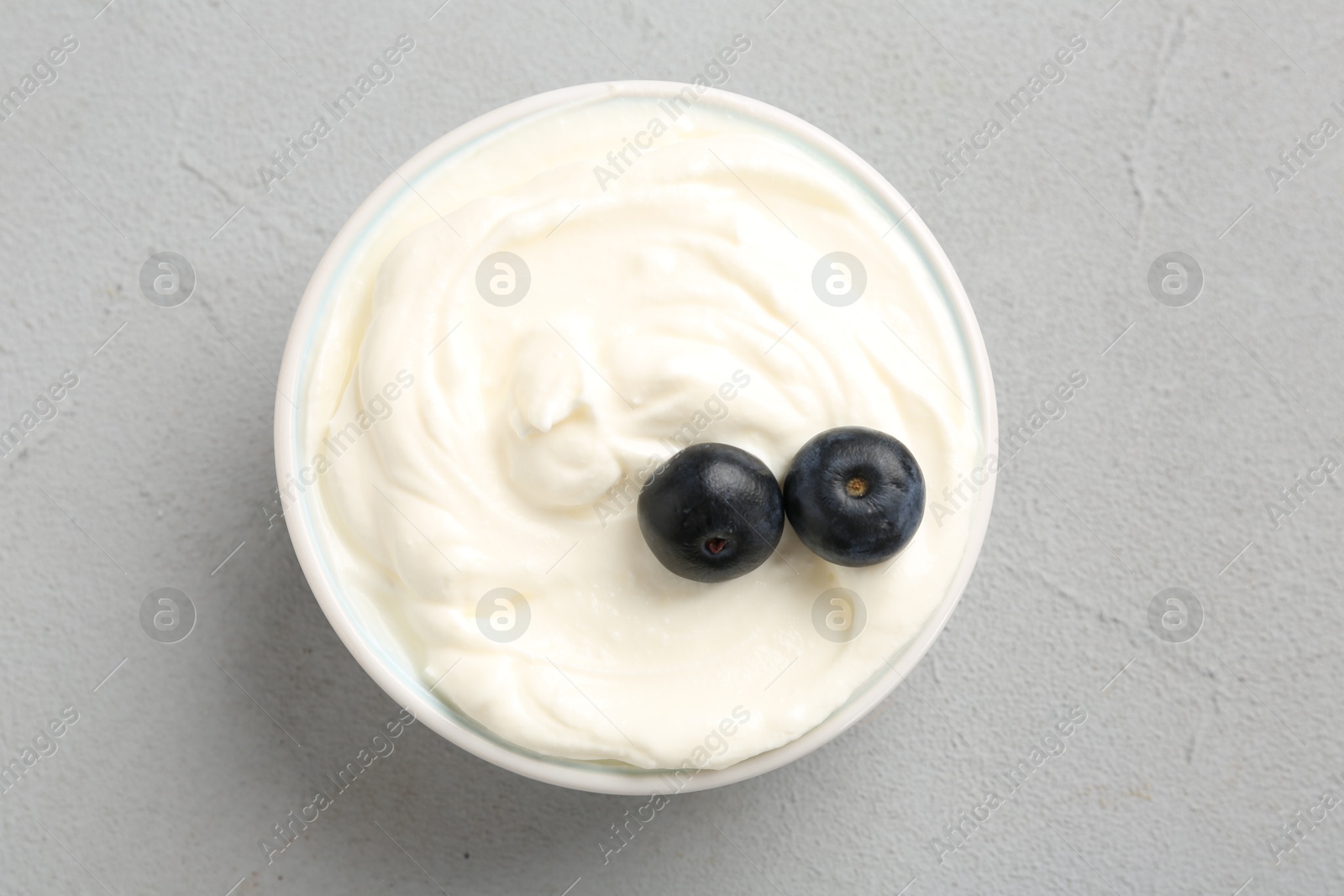 Photo of Delicious yogurt with blueberries in bowl on grey table, top view