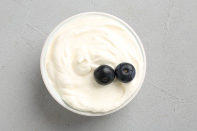 Photo of Delicious yogurt with blueberries in bowl on grey table, top view