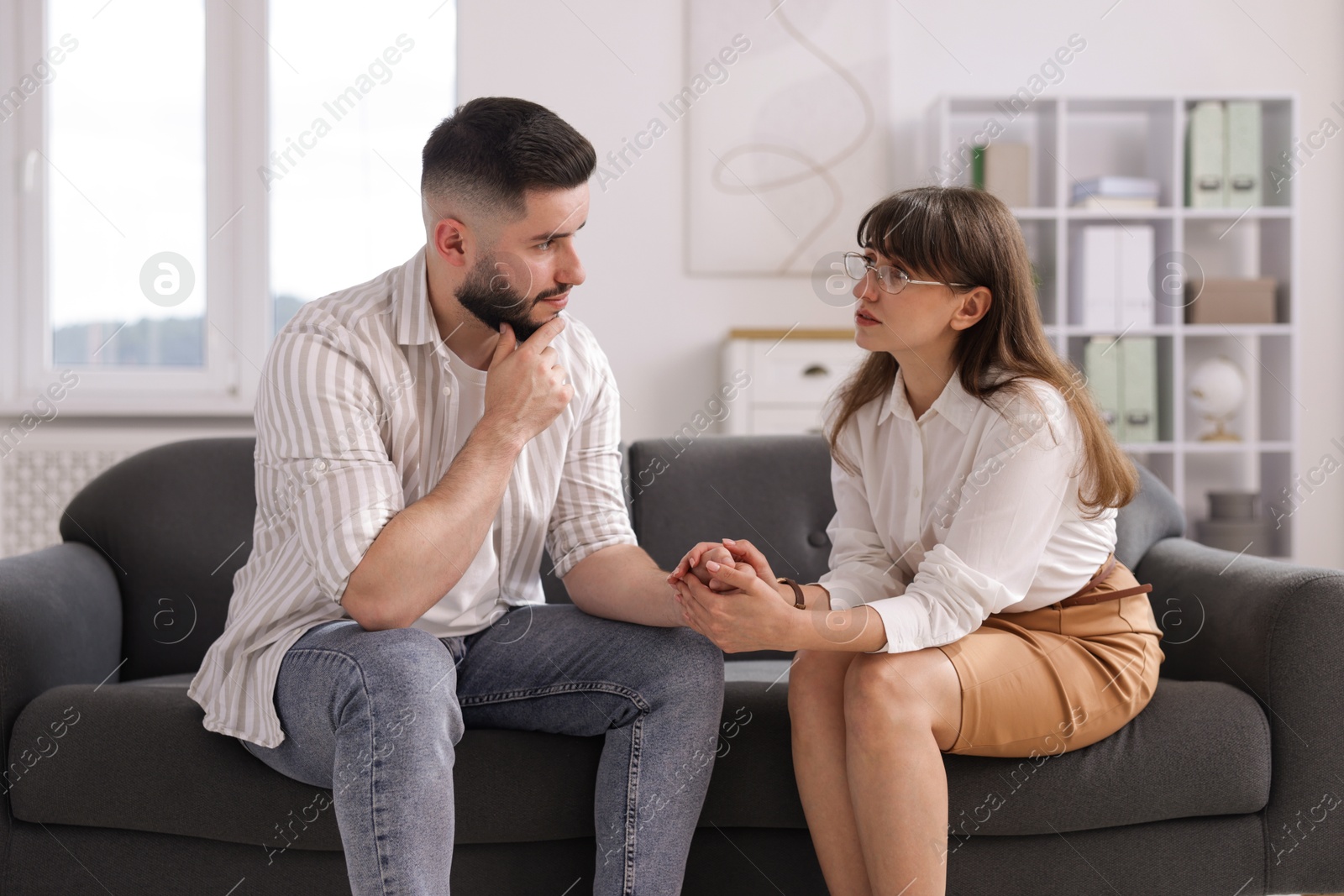 Psychologist supporting patient during therapy session on sofa in office Photo of Psychologist supporting patient during therapy session on sofa in office