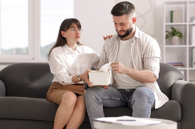 Photo of Psychologist supporting patient during therapy session on sofa in office