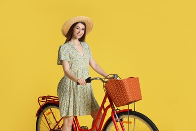Photo of Smiling woman in hat riding bicycle with basket against light green background