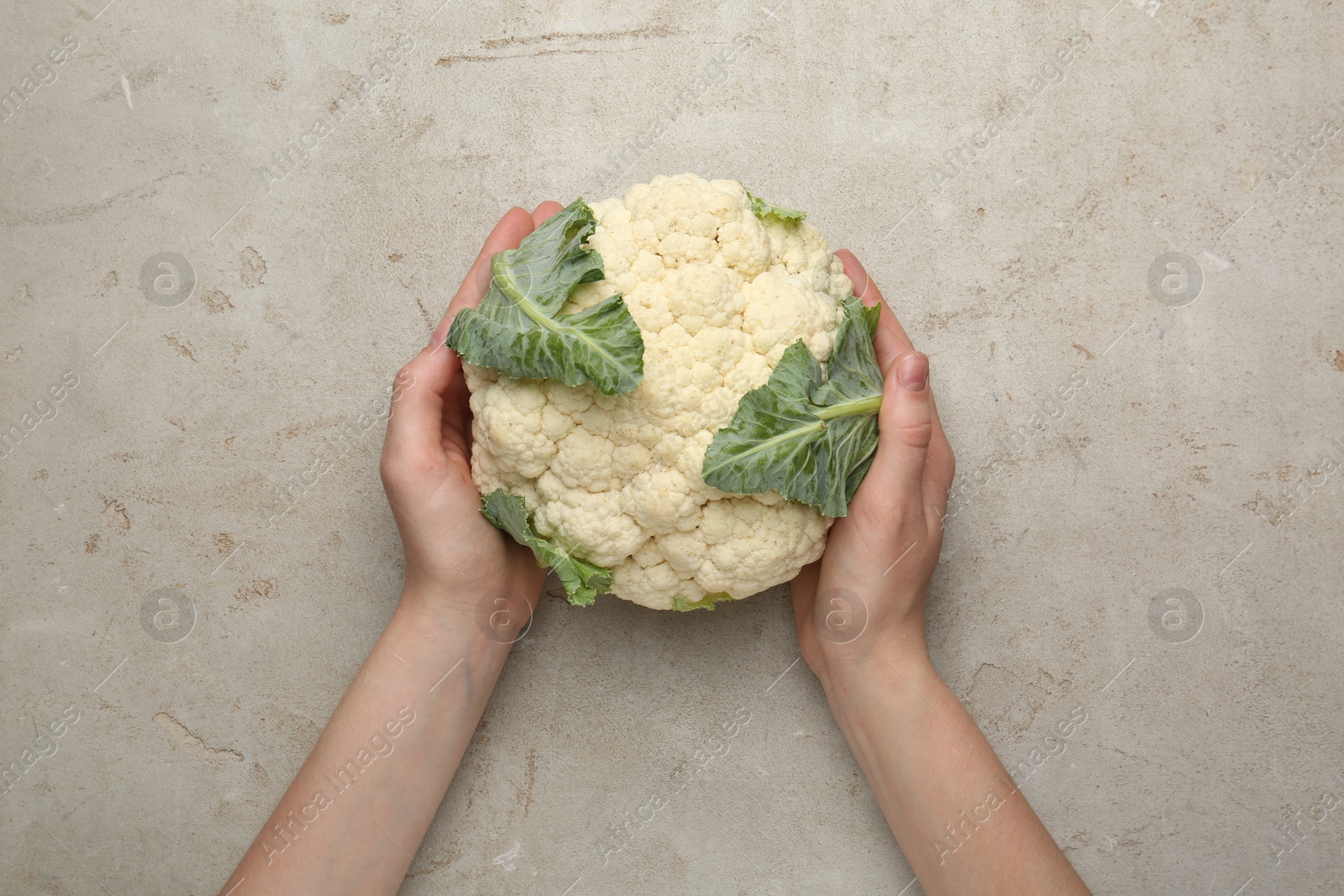 Woman with whole cauliflower at light table, top view Photo of Woman with whole cauliflower at light table, top view