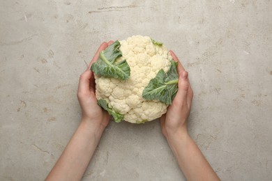 Photo of Woman with whole cauliflower at light table, top view