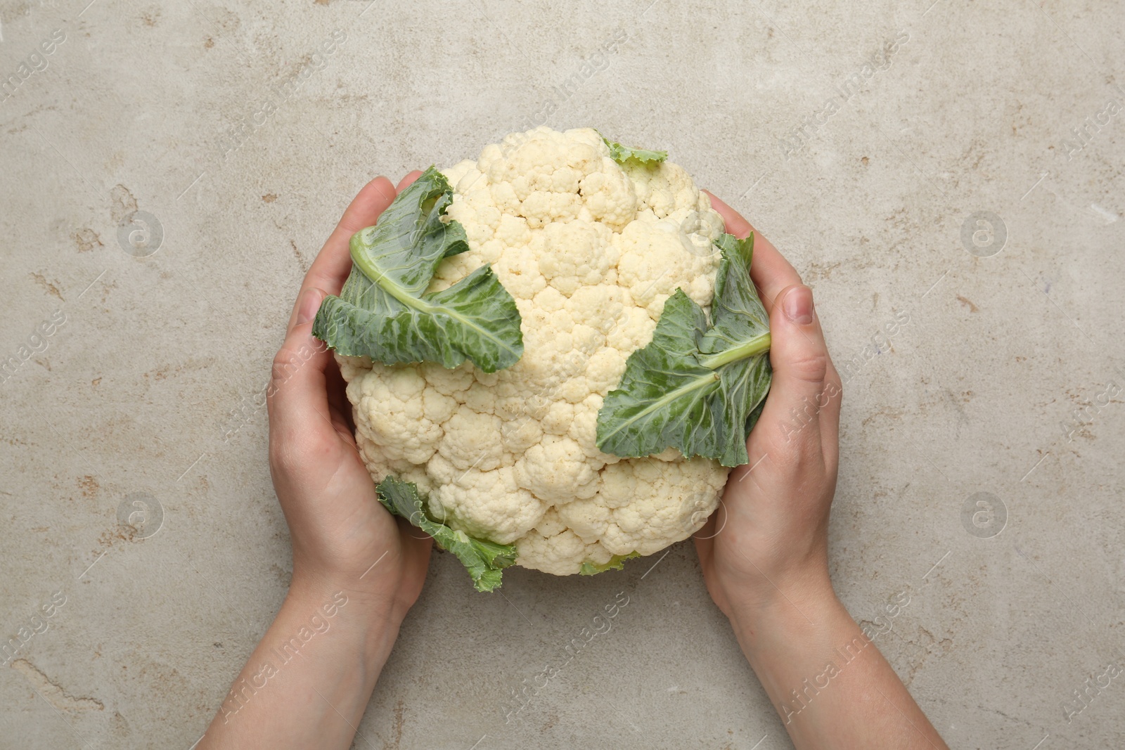 Woman with whole cauliflower at light table, top view Photo of Woman with whole cauliflower at light table, top view