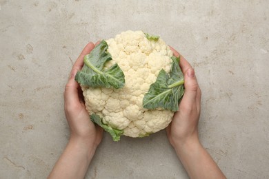 Photo of Woman with whole cauliflower at light table, top view