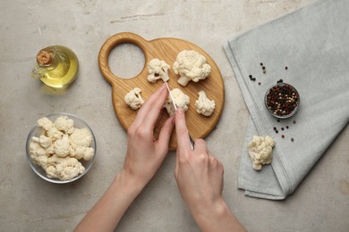 Photo of Woman cutting raw cauliflower at light table, top view