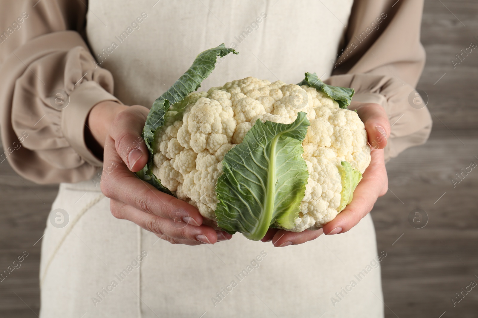 Photo of Woman with whole cauliflower on wooden background, closeup
