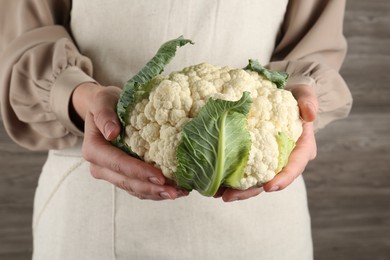 Photo of Woman with whole cauliflower on wooden background, closeup