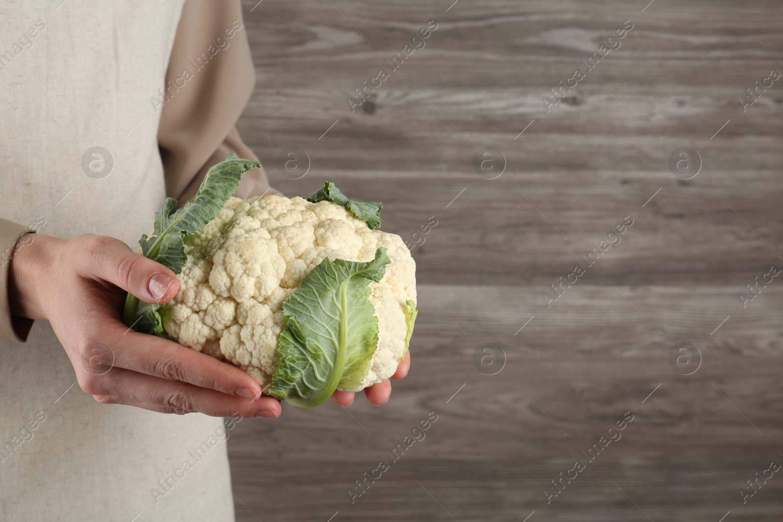 Woman with whole cauliflower on wooden background, closeup. Space for text Photo of Woman with whole cauliflower on wooden background, closeup. Space for text
