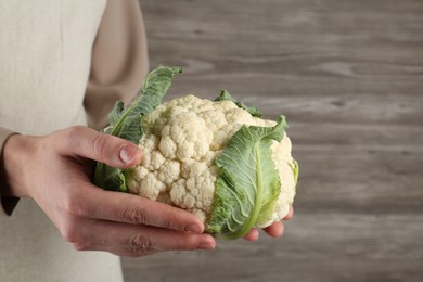 Photo of Woman with whole cauliflower on wooden background, closeup