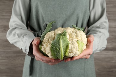 Photo of Woman with whole cauliflower on wooden background, closeup