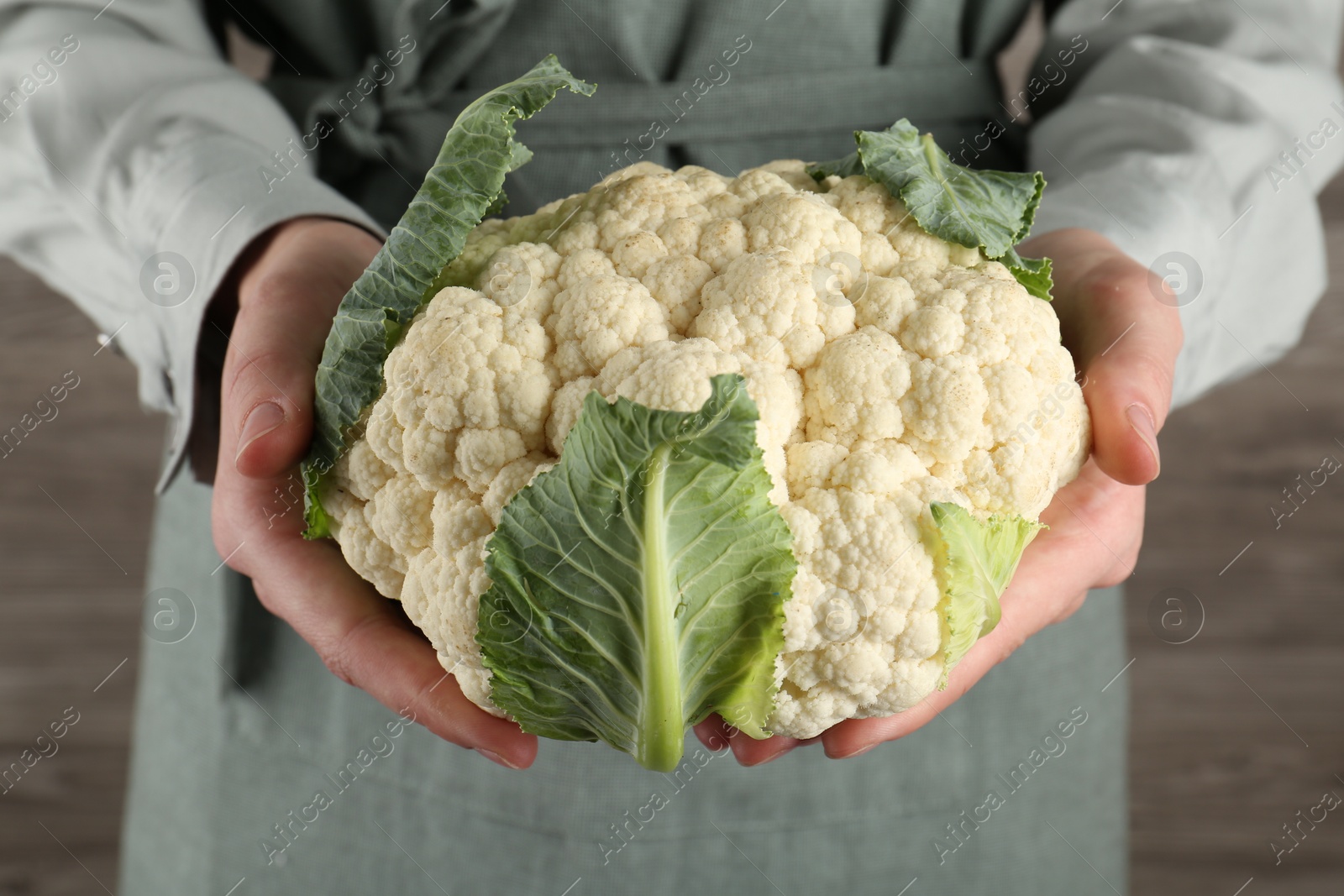 Woman with whole cauliflower on wooden background, closeup Photo of Woman with whole cauliflower on wooden background, closeup