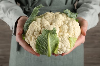 Photo of Woman with whole cauliflower on wooden background, closeup