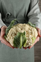 Photo of Woman with whole cauliflower on wooden background, closeup