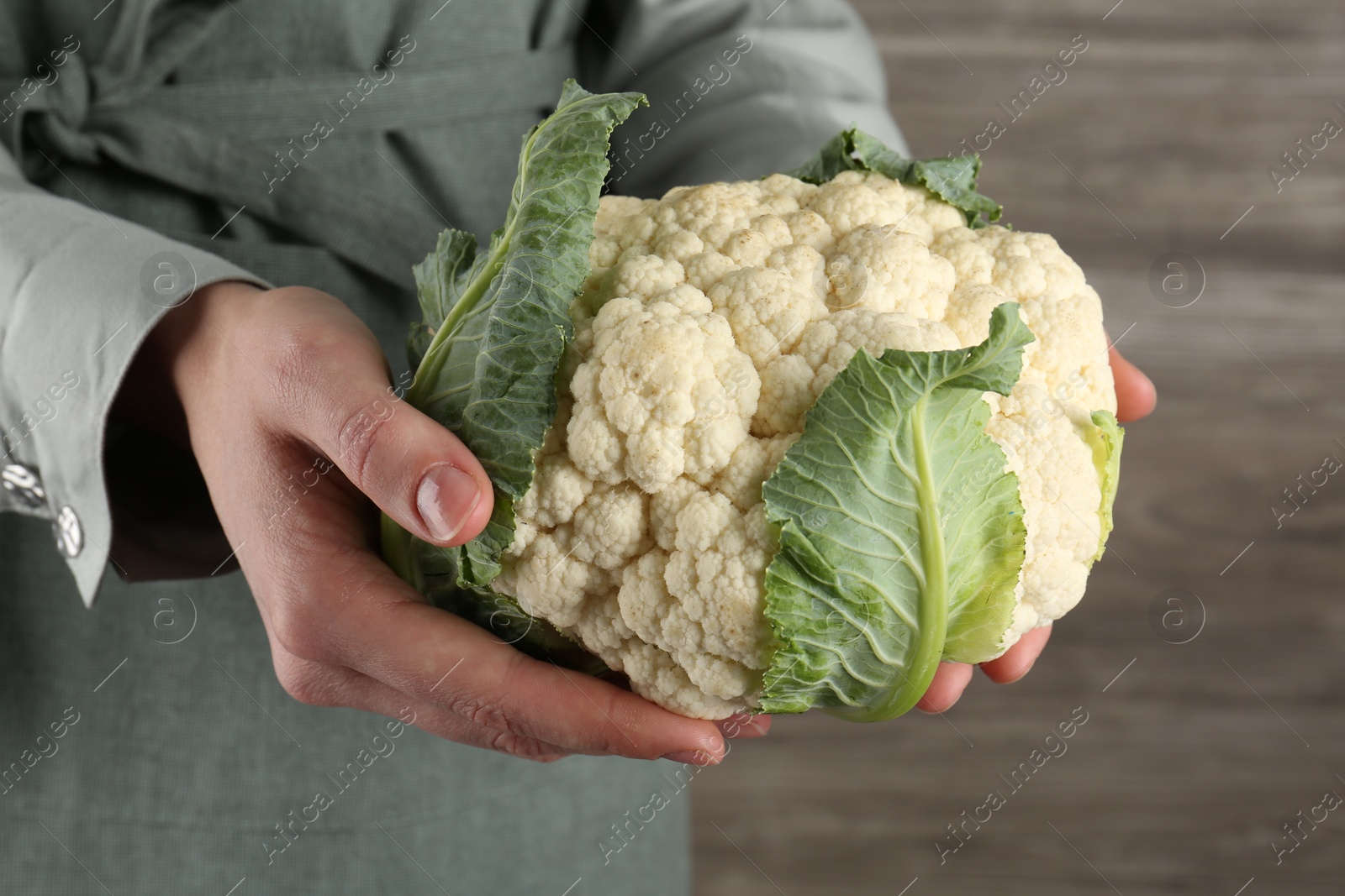 Woman with whole cauliflower on wooden background, closeup Photo of Woman with whole cauliflower on wooden background, closeup