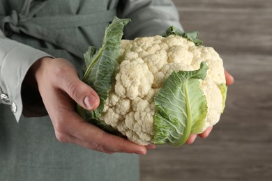 Photo of Woman with whole cauliflower on wooden background, closeup