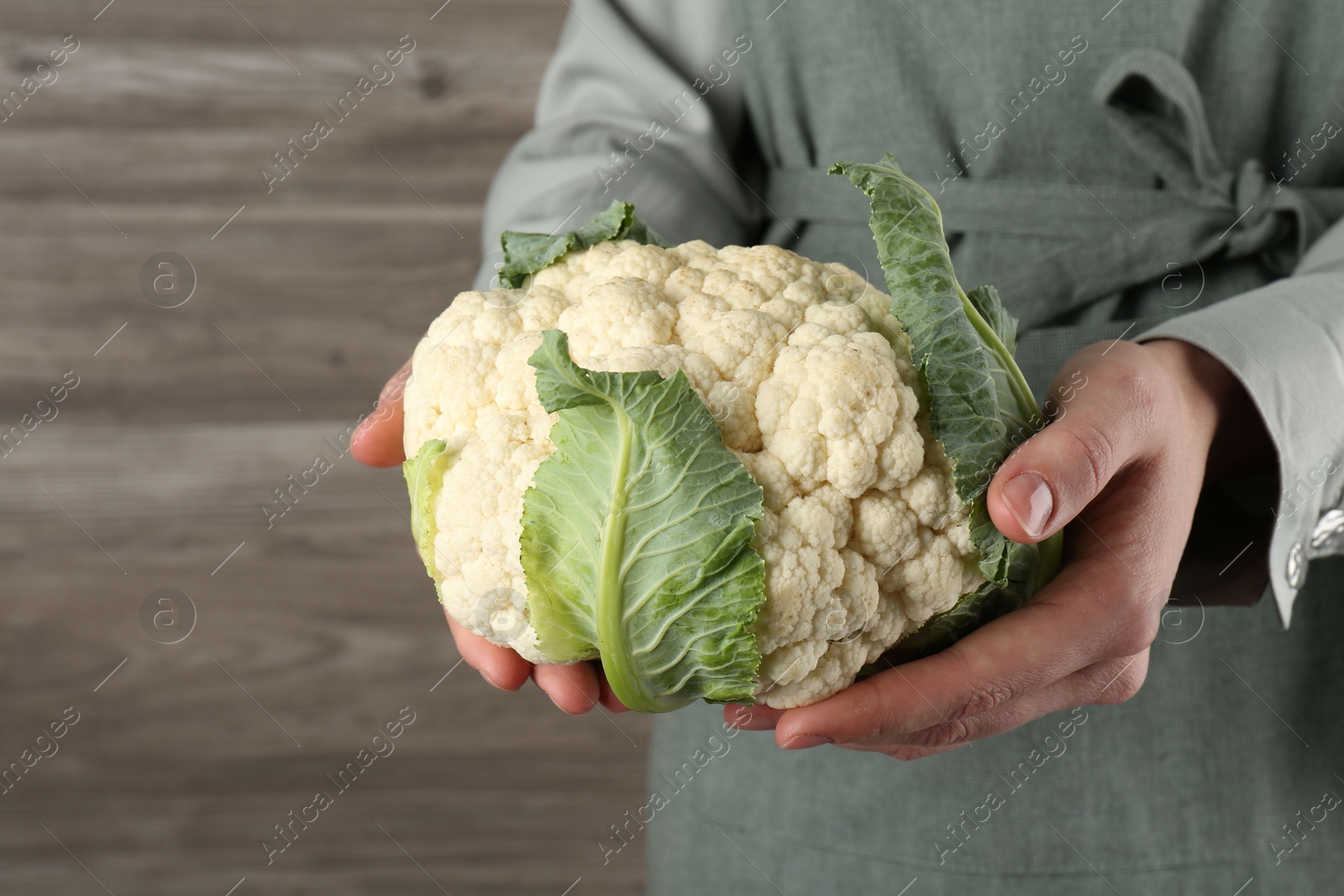 Woman with whole cauliflower on wooden background, closeup Photo of Woman with whole cauliflower on wooden background, closeup