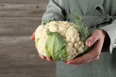 Photo of Woman with whole cauliflower on wooden background, closeup