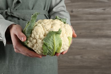Photo of Woman with whole cauliflower on wooden background, closeup