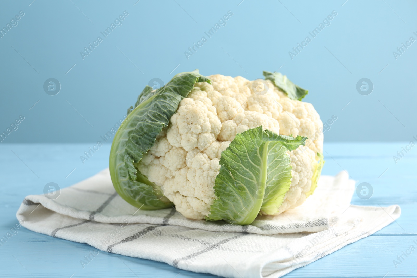 Photo of Whole cauliflower on light blue wooden table, closeup