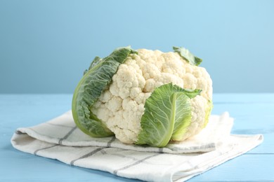 Photo of Whole cauliflower on light blue wooden table, closeup