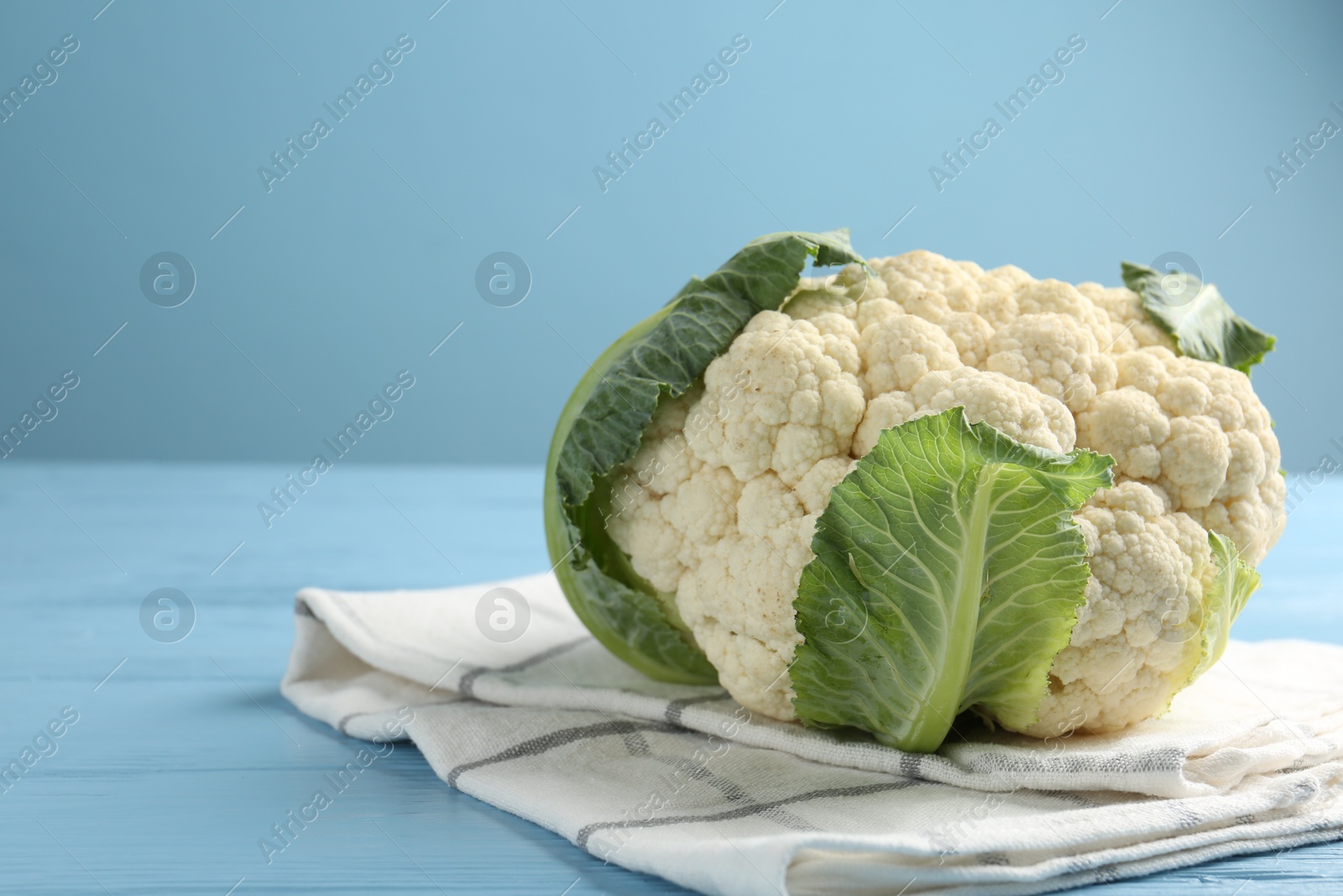 Whole cauliflower on light blue wooden table, closeup. Space for text Photo of Whole cauliflower on light blue wooden table, closeup. Space for text
