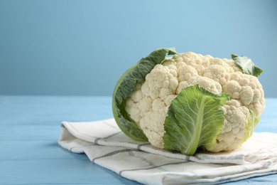 Photo of Whole cauliflower on light blue wooden table, closeup. Space for text