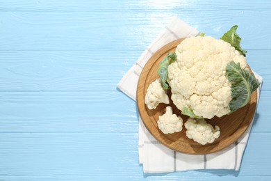 Photo of Raw cauliflower on light blue wooden table, top view. Space for text