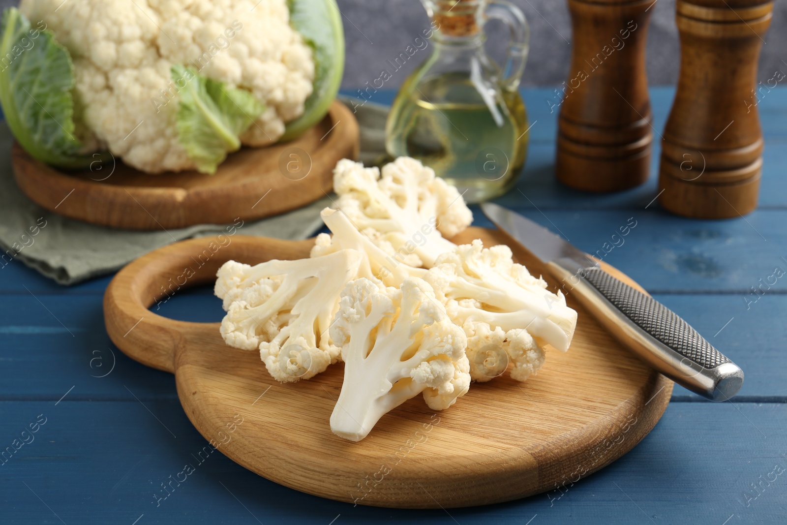 Pieces of cauliflower, knife and spices on blue wooden table, closeup Photo of Pieces of cauliflower, knife and spices on blue wooden table, closeup