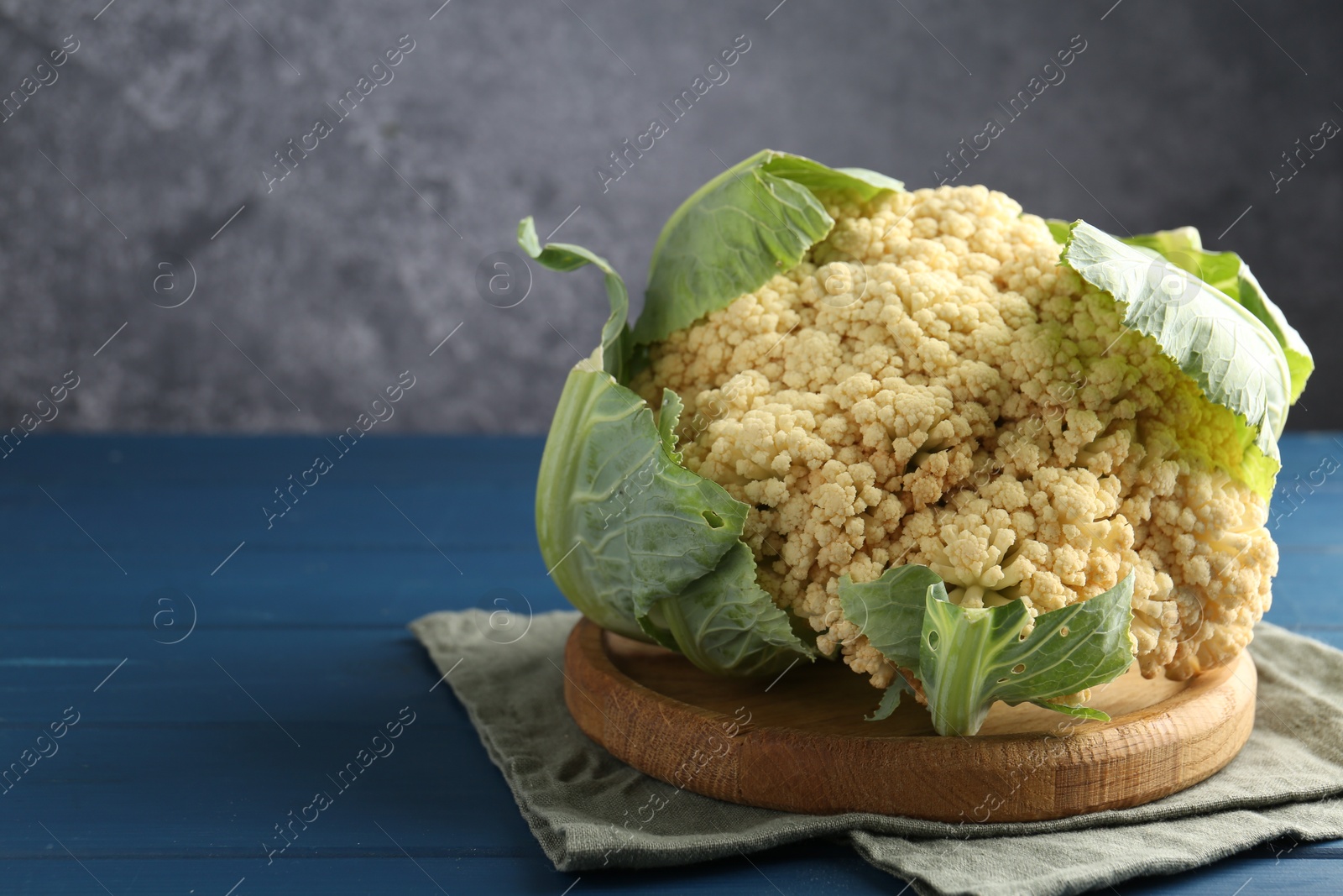 Whole cauliflower on blue wooden table, closeup. Space for text Photo of Whole cauliflower on blue wooden table, closeup. Space for text