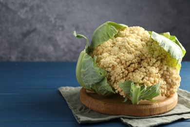Photo of Whole cauliflower on blue wooden table, closeup. Space for text