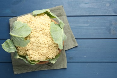 Photo of Whole cauliflower on blue wooden table, top view. Space for text