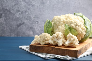 Photo of Raw cauliflower on blue wooden table. Space for text