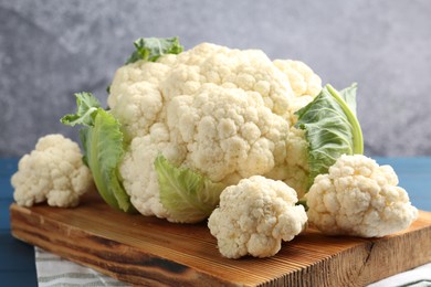 Photo of Raw cauliflower on blue wooden table, closeup