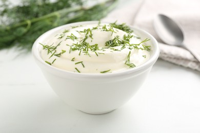Photo of Delicious yogurt in bowl and dill on white table, closeup