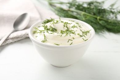 Photo of Delicious yogurt in bowl and dill on white marble table, closeup