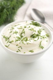 Photo of Delicious yogurt in bowl and dill on white table, closeup