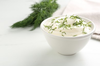 Photo of Delicious yogurt in bowl and dill on white marble table, closeup. Space for text