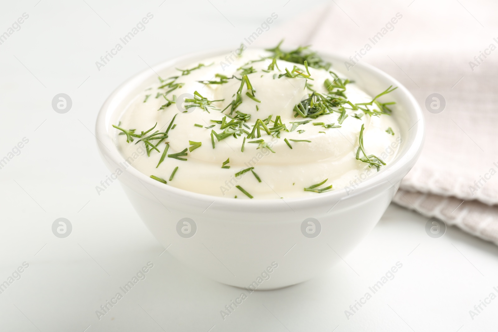 Photo of Delicious yogurt in bowl and dill on white table, closeup