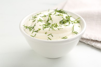 Photo of Delicious yogurt in bowl and dill on white table, closeup