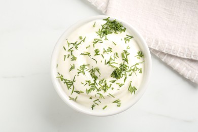 Photo of Delicious yogurt in bowl and dill on white marble table, top view