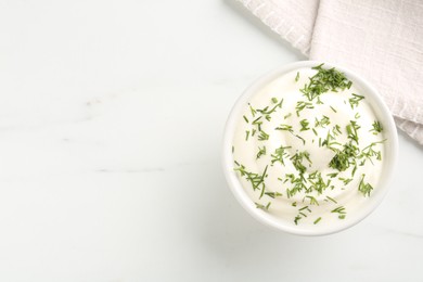Photo of Delicious yogurt in bowl and dill on white marble table, top view. Space for text
