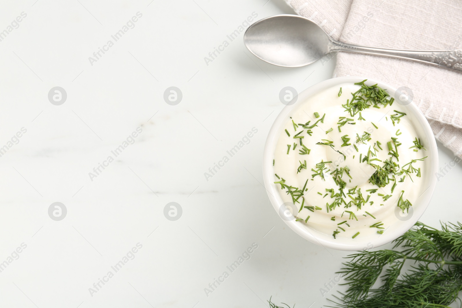 Photo of Delicious yogurt in bowl, dill and spoon on white marble table, flat lay. Space for text