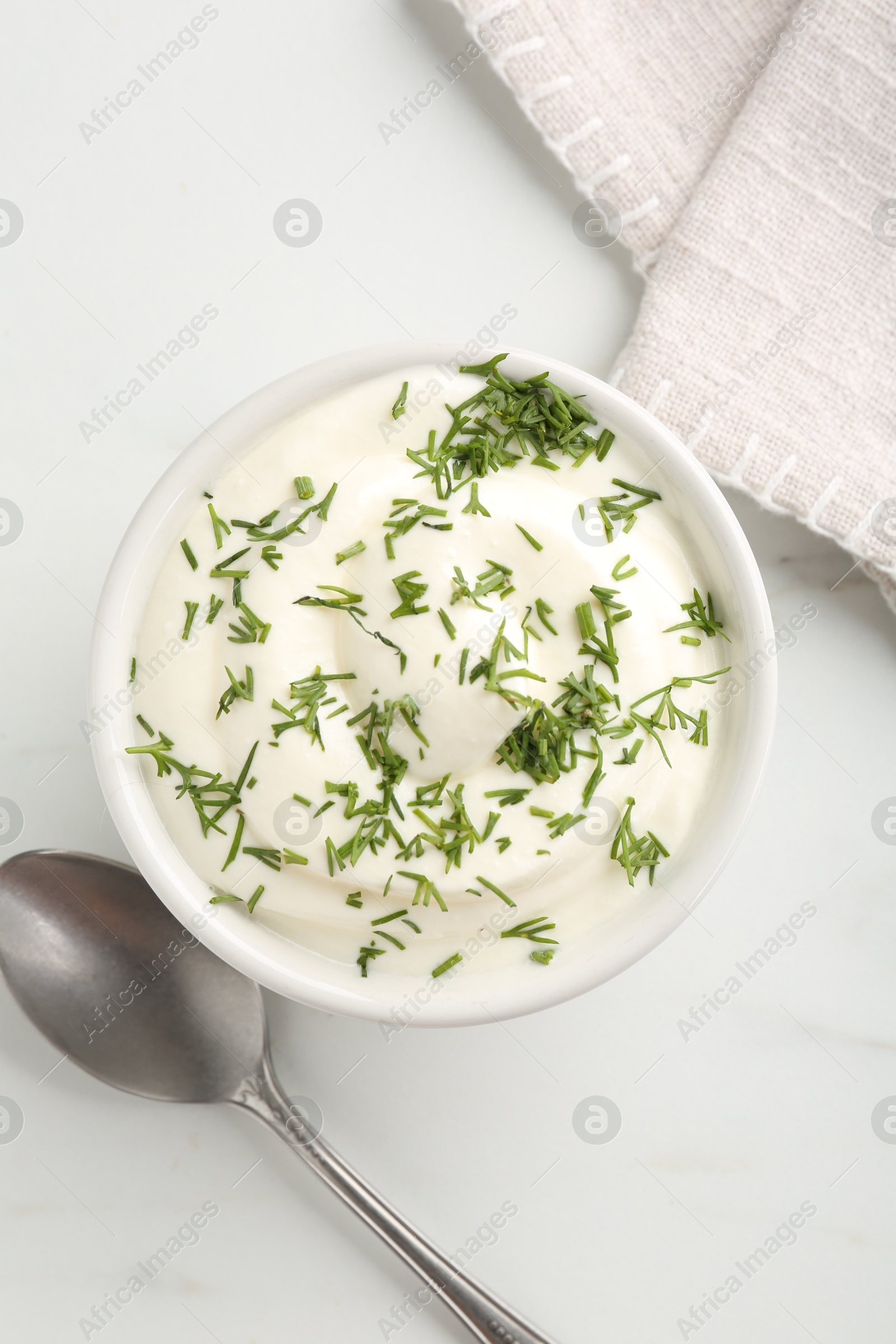 Photo of Delicious yogurt in bowl, dill and spoon on white marble table, flat lay