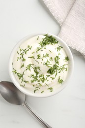 Photo of Delicious yogurt in bowl, dill and spoon on white marble table, flat lay