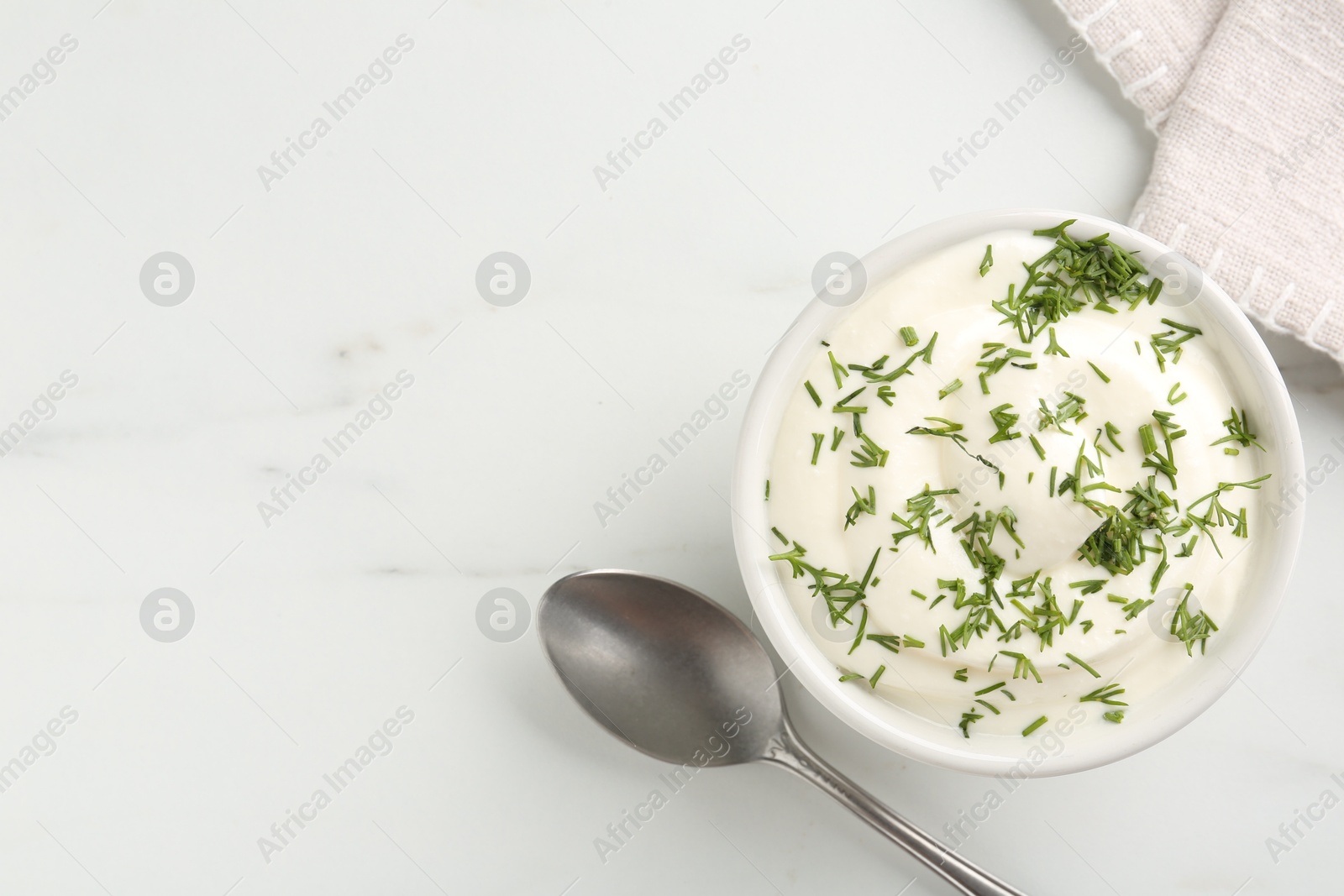 Delicious yogurt in bowl, dill and spoon on white marble table, flat lay. Space for text Photo of Delicious yogurt in bowl, dill and spoon on white marble table, flat lay. Space for text