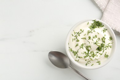 Photo of Delicious yogurt in bowl, dill and spoon on white marble table, flat lay. Space for text