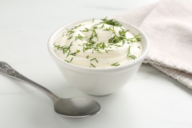Photo of Delicious yogurt in bowl, dill and spoon on white marble table, closeup